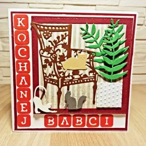 kwadratowa kartka na Dzień Babci ręcznie robiona z fotelem, kotem i napisem Kochanej Babci w czerwonej kolorystyce