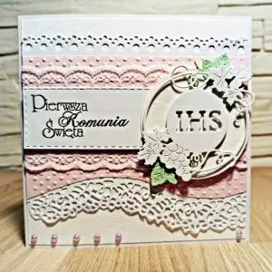 Kwadratowa kartka komunijna 13,5x13,5 dla dziewczynki w odcieniach różu, z centralnym motywem IHS i dekoracyjnymi, koronkowymi pasami, elegancka ręcznie wykonana pamiątka Pierwszej Komunii Świętej