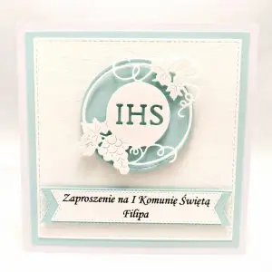 Błękitne zaproszenie na Pierwszą Komunię Świętą dla chłopca z motywem IHS w okręgu, wykonane z białego papieru wizytówkowego, eleganckie zaproszenie komunijne.