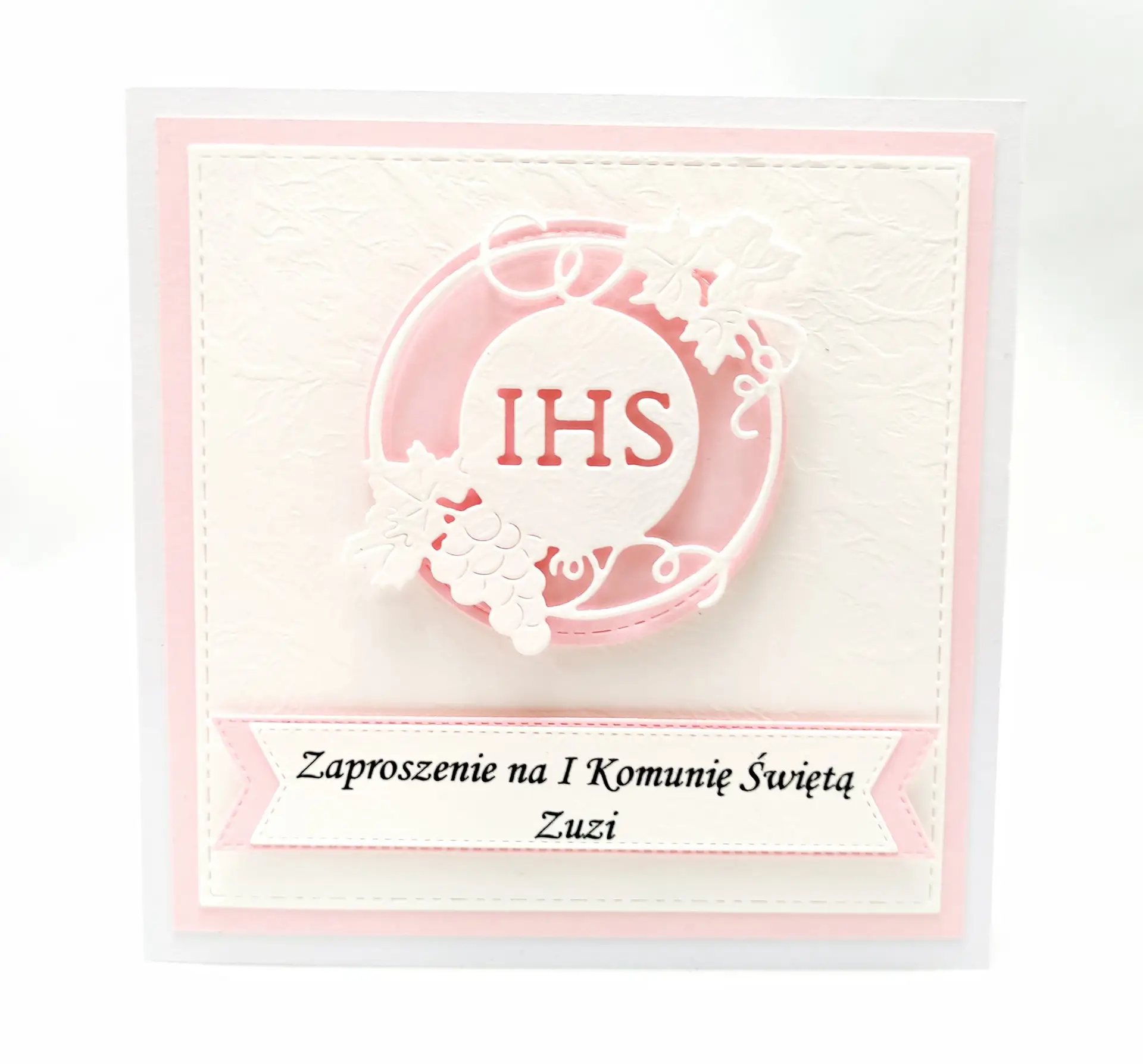 Różowe zaproszenie na Pierwszą Komunię Świętą dla dziewczynki z motywem IHS w okręgu, na białym papierze wizytówkowym, subtelne zaproszenie komunijne.