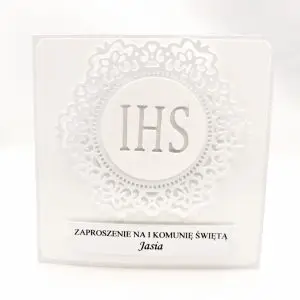 Białe zaproszenie na Pierwszą Komunię Świętą z koronkowym ornamentem i symbolem IHS, wykonane z papieru wizytówkowego, eleganckie kwadratowe zaproszenie w całości w bieli.