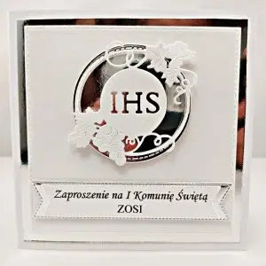Perłowe zaproszenie komunijne w bieli z motywem IHS w srebrnym okręgu na lustrzanym tle, delikatne i eleganckie zaproszenie na Pierwszą Komunię Świętą.