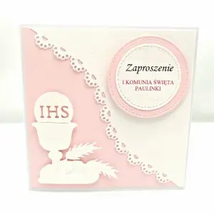 Różowe zaproszenie na Pierwszą Komunię Świętą dla dziewczynki, z motywem kielicha IHS, skośnym różowym tłem i ażurową koronką na białym papierze wizytówkowym.