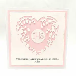 Różowe zaproszenie na Pierwszą Komunię Świętą dla dziewczynki, z sercem z konwalii wokół symbolu IHS, na białym papierze wizytówkowym z różowym tłem.