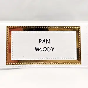 Elegancka winietka z białego papieru perłowego z dodatkiem lustrzanego złota, ustawiona na stole, z miejscem na imię gościa