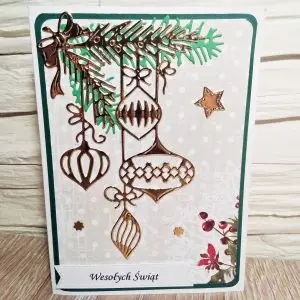 ażurowa kartka świąteczna z gałązką świerku i wiszącymi bombkami oraz napisem Wesołych Świąt, ręcznie robiona kartka na Boże Narodzenie