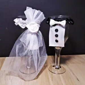 Ręcznie robiona dekoracja na kieliszki Pary Młodej, kieliszki ubrane w suknię ślubną z tiulu i garnitur z muchą, elegancki dodatek na stół weselny
