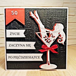 Ręcznie robiona kartka na 50 urodziny z napisem „Życie zaczyna się po pięćdziesiątce”, czarne tło z tłoczeniem, czerwono-białym kieliszkiem i sylwetką kobiety oraz czerwoną kokardką