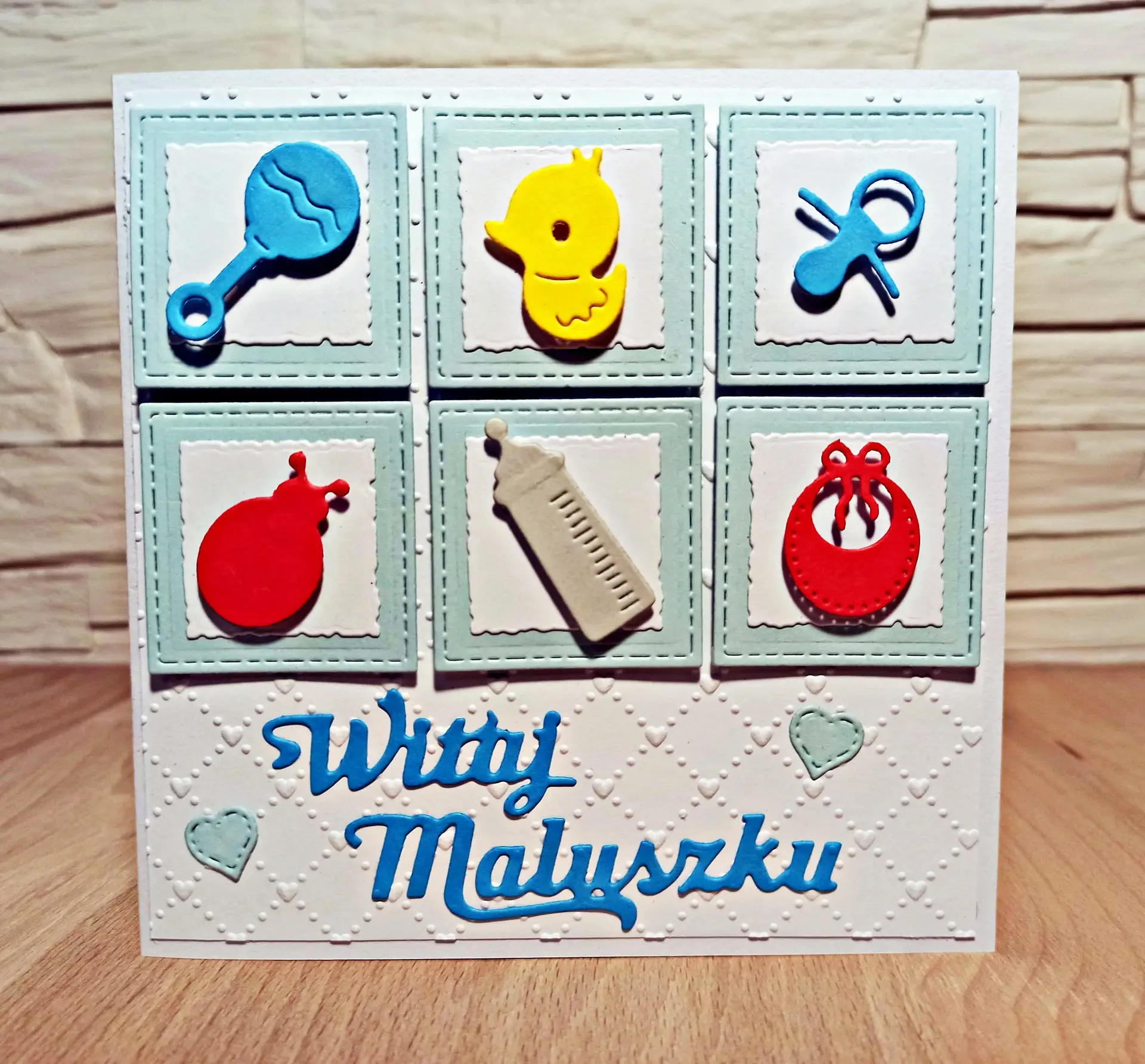 kwadratowa kartka Witaj Maluszku dla chłopca z dziecięcymi gadżetami w niebiesko-pastelowej kolorystyce, ręcznie robiona kartka z okazji narodzin syna