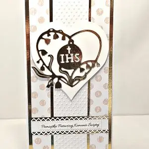 Ręcznie robiona kartka komunijna DL z motywem IHS w ozdobnym sercu i napisem „Pamiątka Pierwszej Komunii Świętej”, delikatne zdobienia i eleganckie tło
