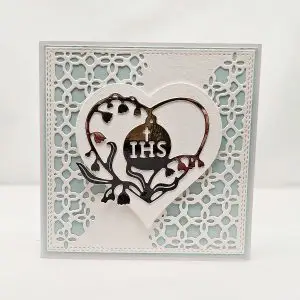Kwadratowa kartka komunijna 13,5x13,5 dla chłopca, w odcieniach niebieskiego, z motywem serca i symbolem IHS na ozdobnym tle, ręcznie wykonana pamiątka Pierwszej Komunii Świętej