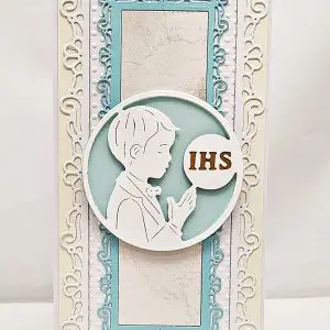 Kartka komunijna DL dla chłopca z postacią chłopca w albie, okrągłym motywem IHS i ozdobnym tłem, elegancka ręcznie wykonana pamiątka Pierwszej Komunii