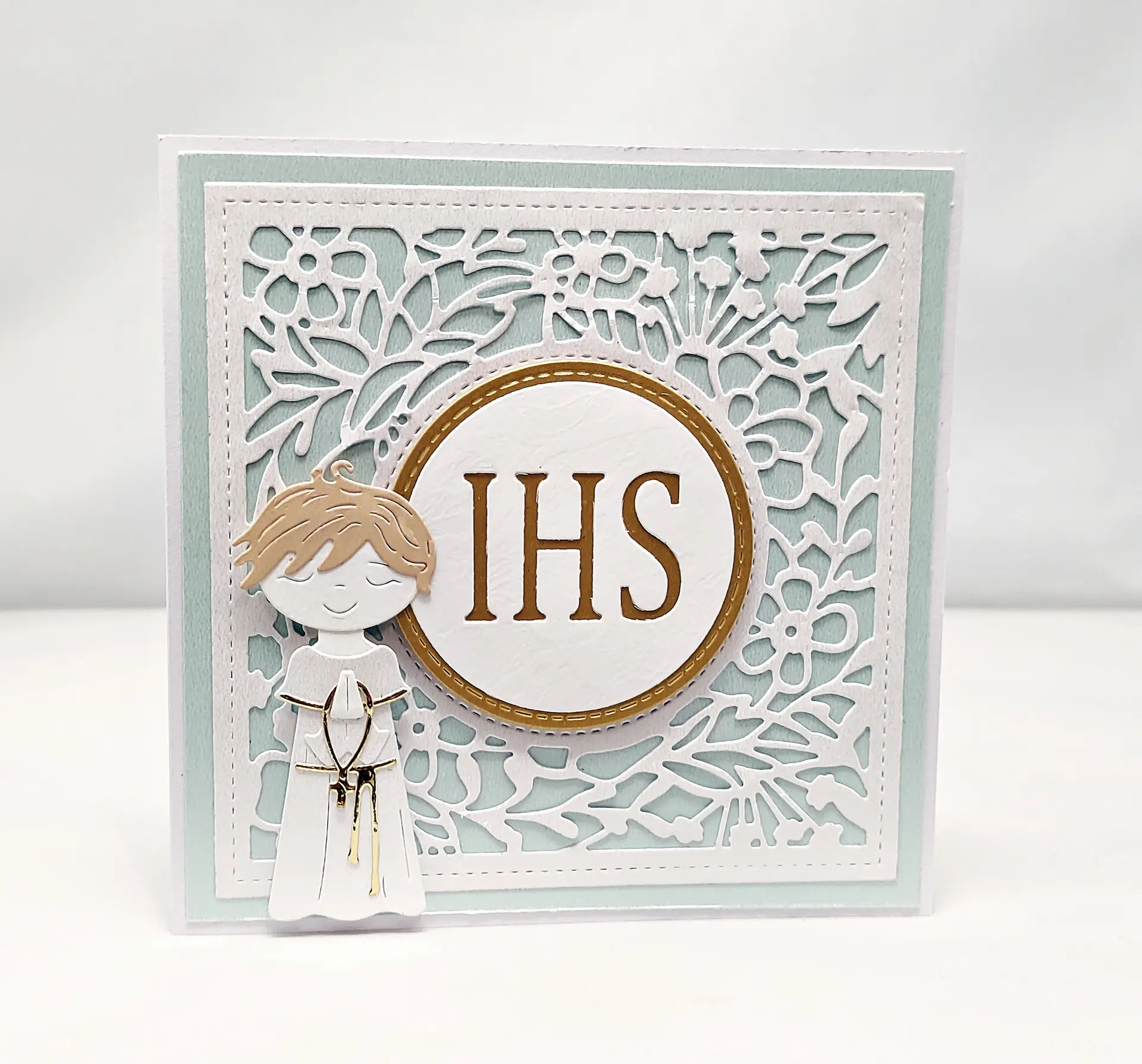 Ręcznie robiona kartka komunijna dla chłopca w odcieniach błękitu, z motywem IHS i postacią chłopca w albie