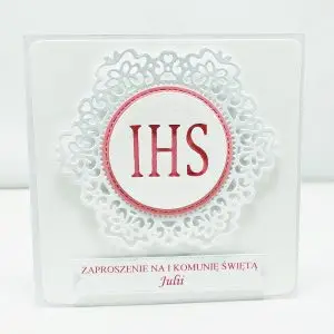 Różowe zaproszenie na Pierwszą Komunię Świętą z białym koronkowym ornamentem i symbolem IHS, kwadratowe, na papierze wizytówkowym, elegancka dziewczęca wersja zaproszenia.