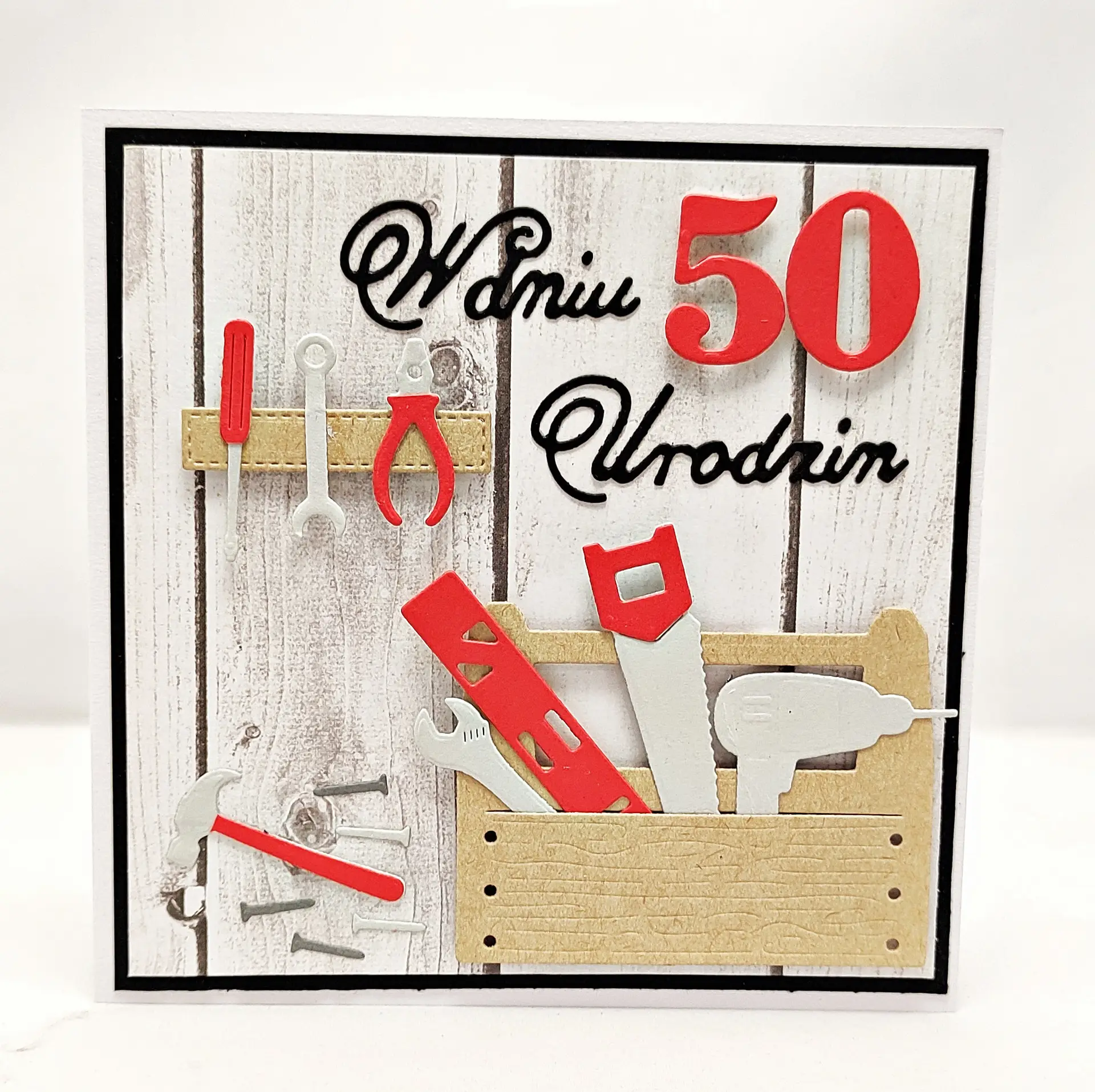 Ręcznie robiona kartka na 50 urodziny dla mężczyzny, motyw majsterkowicza, skrzynka z narzędziami, młotek, wkrętarka, napis „W dniu 50 Urodzin” na tle drewna