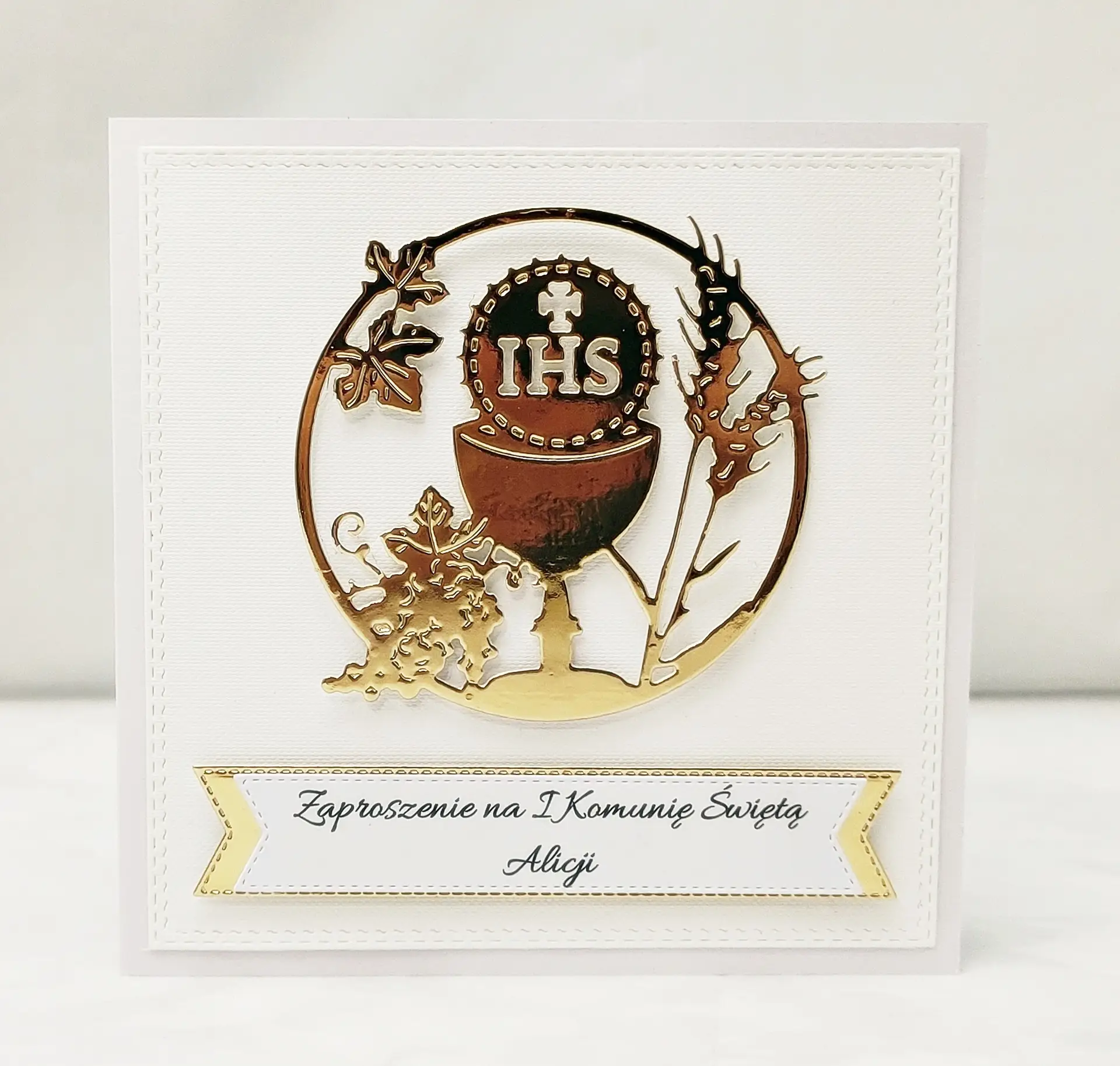 Zaproszenie na Pierwszą Komunię Świętą z kielichem i symbolem IHS w okręgu, na białym papierze wizytówkowym, eleganckie biało-złote zaproszenie bez lustrzanego tła.