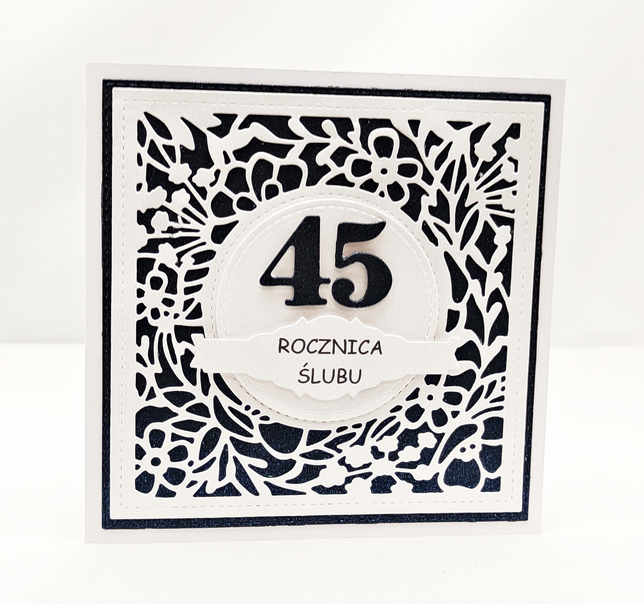 Ręcznie robiona kartka na 45 rocznicę ślubu, kwadratowa, z ażurową kwiatową ramką i granatowym szafirowym tłem, z dużą cyfrą 45 i napisem „Rocznica ślubu”