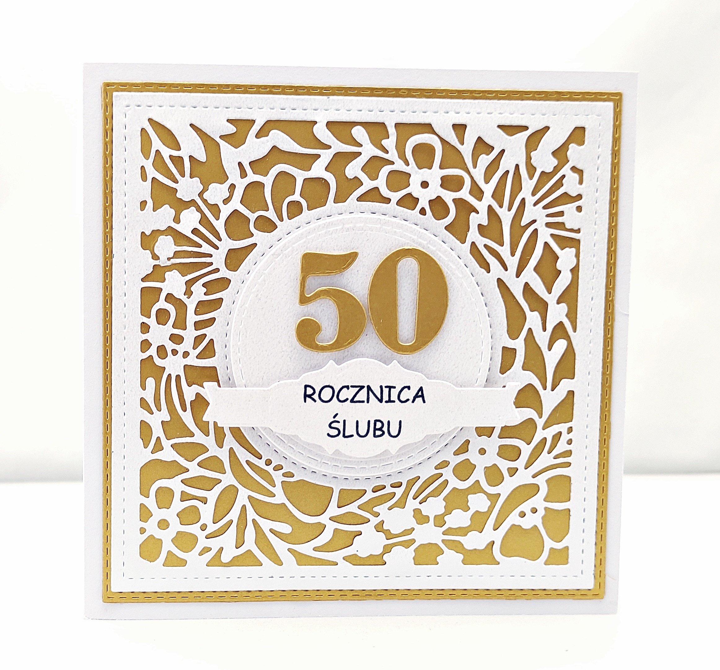 Ręcznie robiona kartka na 50 rocznicę ślubu, kwadratowa, z ażurową kwiatową ramką i złotym tłem, z dużą cyfrą 50 i napisem „Rocznica ślubu”